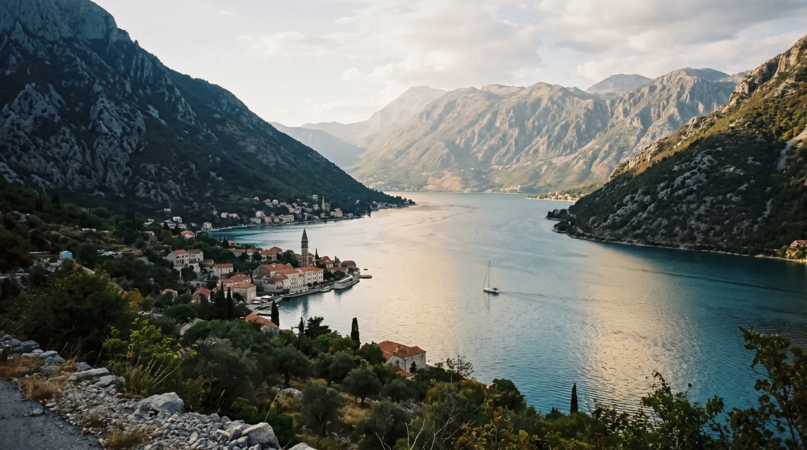 The Bay of Kotor seen from above, mountains falling into calm water with towns along the shore